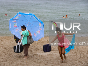 Two women are leaving a beach as it rains in Odesa, Ukraine, on July 22, 2024. (