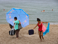 Two women are leaving a beach as it rains in Odesa, Ukraine, on July 22, 2024. (