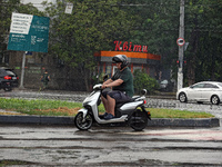 A man is riding a scooter along the road in the rain in Odesa, Ukraine, on July 22, 2024. NO USE RUSSIA. NO USE BELARUS. (