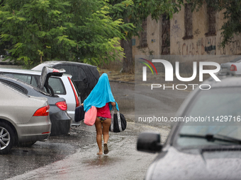 A woman is leaving a beach covered with a towel as it rains in Odesa, Ukraine, on July 22, 2024. NO USE RUSSIA. NO USE BELARUS. (