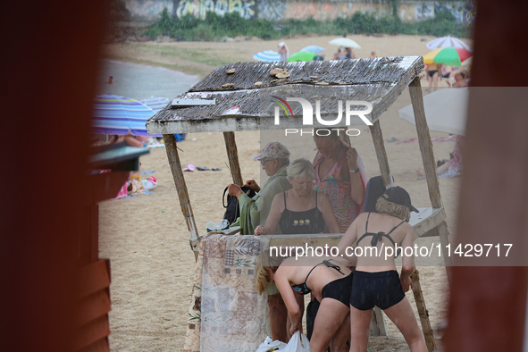 People are hiding from the rain on the beach by the Black Sea in Odesa, Ukraine, on July 22, 2024. NO USE RUSSIA. NO USE BELARUS. 