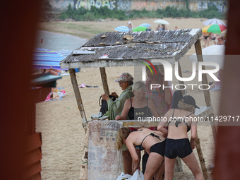 People are hiding from the rain on the beach by the Black Sea in Odesa, Ukraine, on July 22, 2024. NO USE RUSSIA. NO USE BELARUS. (