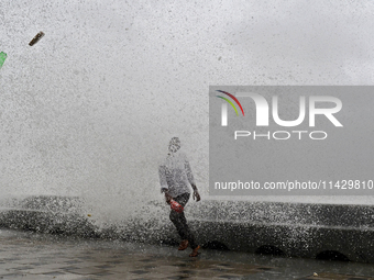 Visitors are reacting to sea waves at the Marine Drive promenade during high tide in Mumbai, India, on July 23, 2024. (