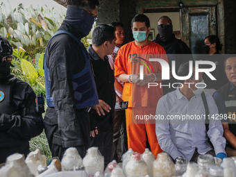 Indonesian National Narcotic Agency (BNN) officers are escorting the suspect after a raid of a drug lab, during a press conference in Gianya...