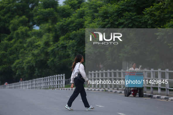 A Nepali citizen is crossing the road against the backdrop of plants planted on the roadside that have turned clean and green after overnigh...