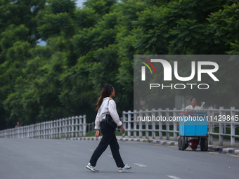 A Nepali citizen is crossing the road against the backdrop of plants planted on the roadside that have turned clean and green after overnigh...