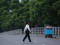 A Nepali citizen is crossing the road against the backdrop of plants planted on the roadside that have turned clean and green after overnigh...