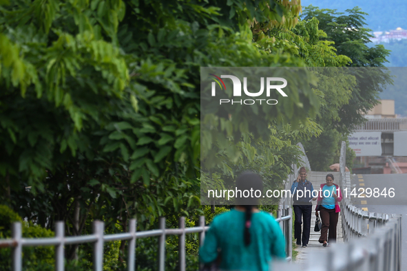 Nepali citizens are walking past the plants planted on the roadside that have turned clean and green after overnight rainfall, which is brin...