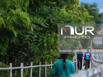 Nepali citizens are walking past the plants planted on the roadside that have turned clean and green after overnight rainfall, which is brin...