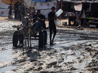 Palestinians are riding a donkey-drawn cart past a garbage dump and sewage water on a street in Deir el-Balah in the central Gaza Strip, on...