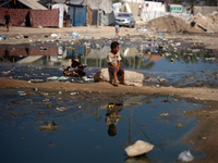 A Palestinian boy is sitting on a street flooded with sewage water in Deir el-Balah in the central Gaza Strip on July 23, 2024, as municipal...