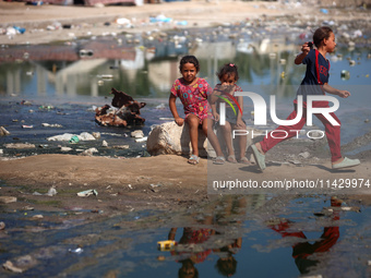 Palestinian children are sitting on a street flooded with sewage water in Deir el-Balah, in the central Gaza Strip, on July 23, 2024, as mun...