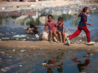 Palestinian children are sitting on a street flooded with sewage water in Deir el-Balah, in the central Gaza Strip, on July 23, 2024, as mun...