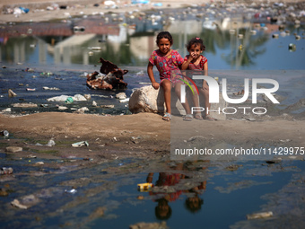 Palestinian children are sitting on a street flooded with sewage water in Deir el-Balah, in the central Gaza Strip, on July 23, 2024, as mun...