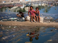 Palestinian children are sitting on a street flooded with sewage water in Deir el-Balah, in the central Gaza Strip, on July 23, 2024, as mun...