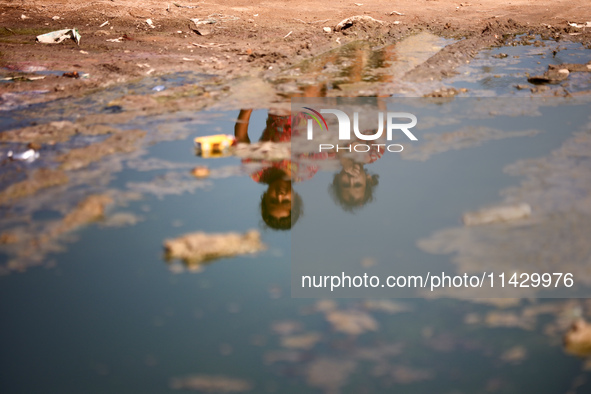 Palestinian children are sitting on a street flooded with sewage water in Deir el-Balah, in the central Gaza Strip, on July 23, 2024, as mun...