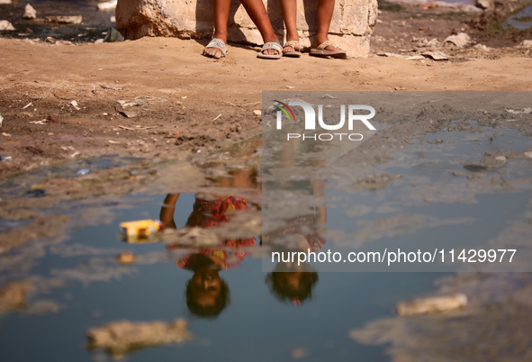 Palestinian children are sitting on a street flooded with sewage water in Deir el-Balah, in the central Gaza Strip, on July 23, 2024, as mun...