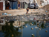 Palestinian children are walking past a pool of sewage water on a street in Deir el-Balah in the central Gaza Strip on July 23, 2024, as mun...