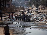 Palestinians are walking past sewage water and a garbage dump on a street in Deir el-Balah in the central Gaza Strip, on July 23, 2024, as m...