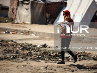 Palestinians are walking past a pool of sewage water on a street in Deir el-Balah in the central Gaza Strip on July 23, 2024, as municipal i...