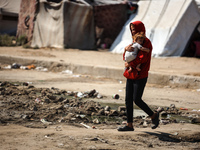 Palestinians are walking past a pool of sewage water on a street in Deir el-Balah in the central Gaza Strip on July 23, 2024, as municipal i...