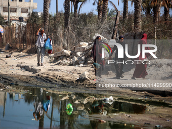 Palestinians are walking past a pool of sewage water on a street in Deir el-Balah in the central Gaza Strip on July 23, 2024, as municipal i...