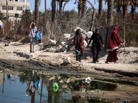 Palestinians are walking past a pool of sewage water on a street in Deir el-Balah in the central Gaza Strip on July 23, 2024, as municipal i...