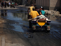 Palestinians are walking past a pool of sewage water on a street in Deir el-Balah in the central Gaza Strip on July 23, 2024, as municipal i...