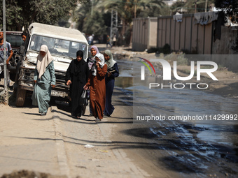 Palestinians are walking past a pool of sewage water on a street in Deir el-Balah in the central Gaza Strip on July 23, 2024, as municipal i...