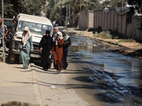 Palestinians are walking past a pool of sewage water on a street in Deir el-Balah in the central Gaza Strip on July 23, 2024, as municipal i...