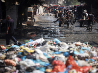 Palestinians are walking past sewage water and a garbage dump on a street in Deir el-Balah in the central Gaza Strip, on July 23, 2024, as m...