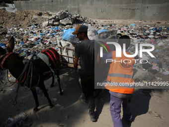 Palestinians are riding a donkey-drawn cart past a garbage dump and sewage water on a street in Deir el-Balah in the central Gaza Strip, on...