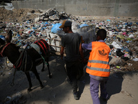 Palestinians are riding a donkey-drawn cart past a garbage dump and sewage water on a street in Deir el-Balah in the central Gaza Strip, on...