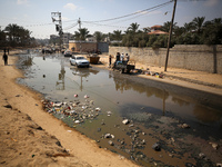 Palestinians are walking past a pool of sewage water on a street in Deir el-Balah in the central Gaza Strip on July 23, 2024, as municipal i...