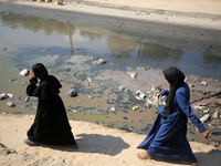 Palestinians are walking past a pool of sewage water on a street in Deir el-Balah in the central Gaza Strip on July 23, 2024, as municipal i...