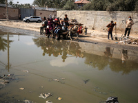 Palestinians are walking past a pool of sewage water on a street in Deir el-Balah in the central Gaza Strip on July 23, 2024, as municipal i...