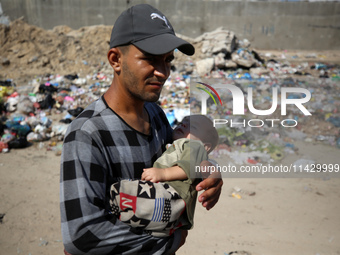 Palestinians are walking past sewage water and a garbage dump on a street in Deir el-Balah in the central Gaza Strip, on July 23, 2024, as m...