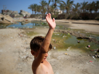 A Palestinian boy is suffering from a skin rash and is standing past a pool of sewage water on a street in Deir el-Balah in the central Gaza...