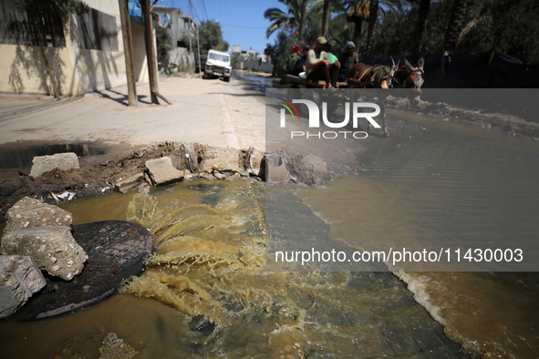 Palestinians are walking past sewage water and a garbage dump on a street in Deir el-Balah in the central Gaza Strip, on July 23, 2024, as m...