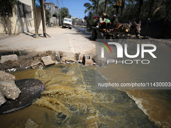 Palestinians are walking past sewage water and a garbage dump on a street in Deir el-Balah in the central Gaza Strip, on July 23, 2024, as m...