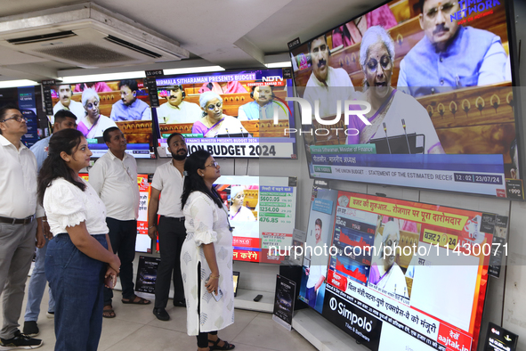 People are watching TV live as Union Finance Minister Nirmala Sitharaman addresses at an electronic shop in Kolkata, India, on July 23, 2024...