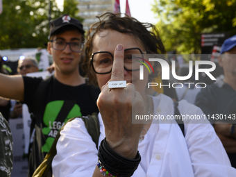 A woman is showing the middle finger as she is wearing a ring that reads ''Fuck off'' during a rally in favor of free and safe abortion in W...