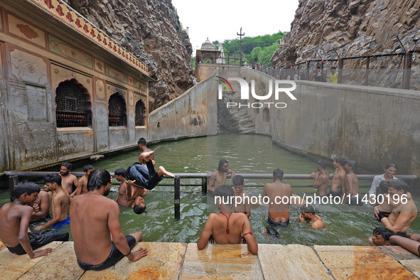 Youth are cooling off in the holy pond 'Kund' of Shrine Galta Peeth Tirtha, also famous as 'Galta Ji temple' and 'Monkey temple', in Jaipur,...