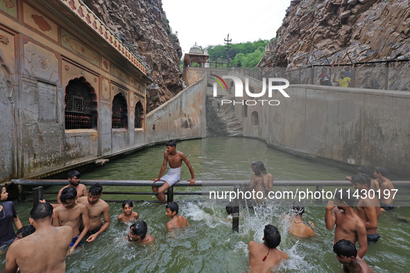 Youth are cooling off in the holy pond 'Kund' of Shrine Galta Peeth Tirtha, also famous as 'Galta Ji temple' and 'Monkey temple', in Jaipur,...