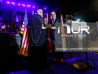 Archbishop ELPIDOPHOROS of America (L) is receiving a commemorative plaque from Supreme President SAVAS TSIVICOS (R) during the ceremony in...