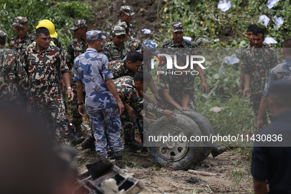 Rescuers from Nepal's security agencies are pulling off the wheel of the crashed passenger aircraft of Saurya Airlines at Tribhuvan Internat...