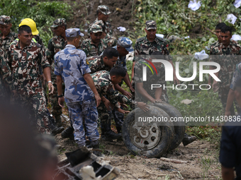 Rescuers from Nepal's security agencies are pulling off the wheel of the crashed passenger aircraft of Saurya Airlines at Tribhuvan Internat...