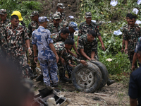 Rescuers from Nepal's security agencies are pulling off the wheel of the crashed passenger aircraft of Saurya Airlines at Tribhuvan Internat...