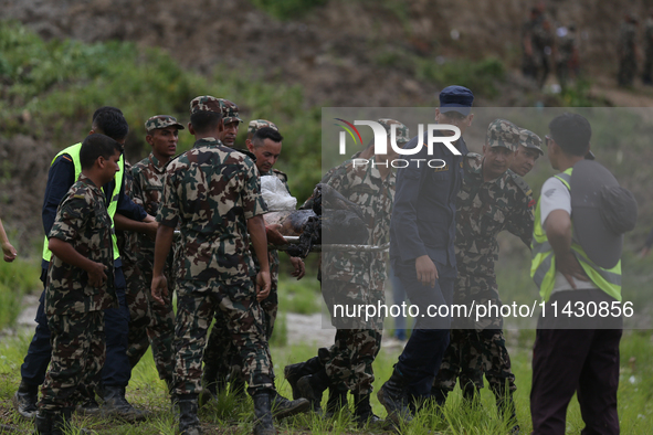 Rescuers from Nepal's security agencies are carrying charred bodies of a dead passenger retrieved from a passenger aircraft of Saurya Airlin...