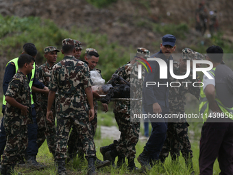 Rescuers from Nepal's security agencies are carrying charred bodies of a dead passenger retrieved from a passenger aircraft of Saurya Airlin...